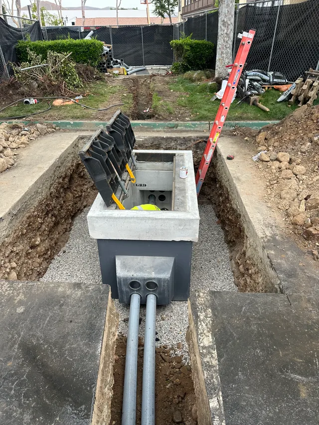 Precast electrical vault set in an open trench with conduit runs entering
