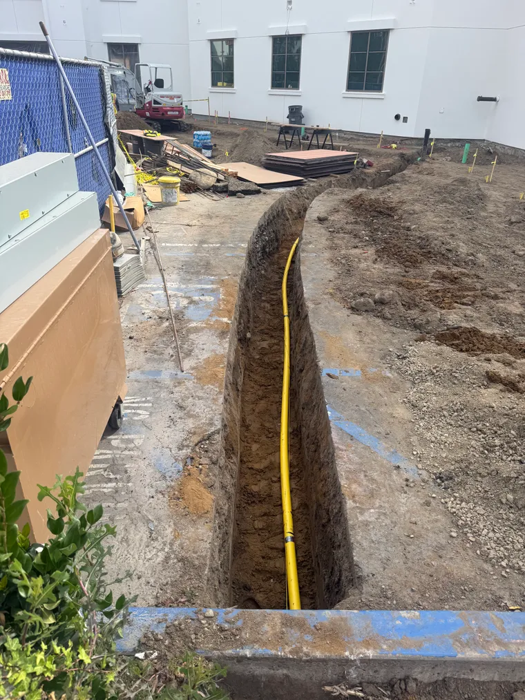 Yellow gas line in an open utility trench excavated and backfilled to utility spec