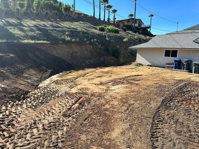 Graded building pad cut into a hillside next to a residence