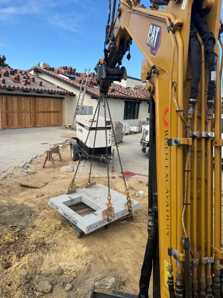 Risen Excavation excavator setting a precast utility vault at a residential project